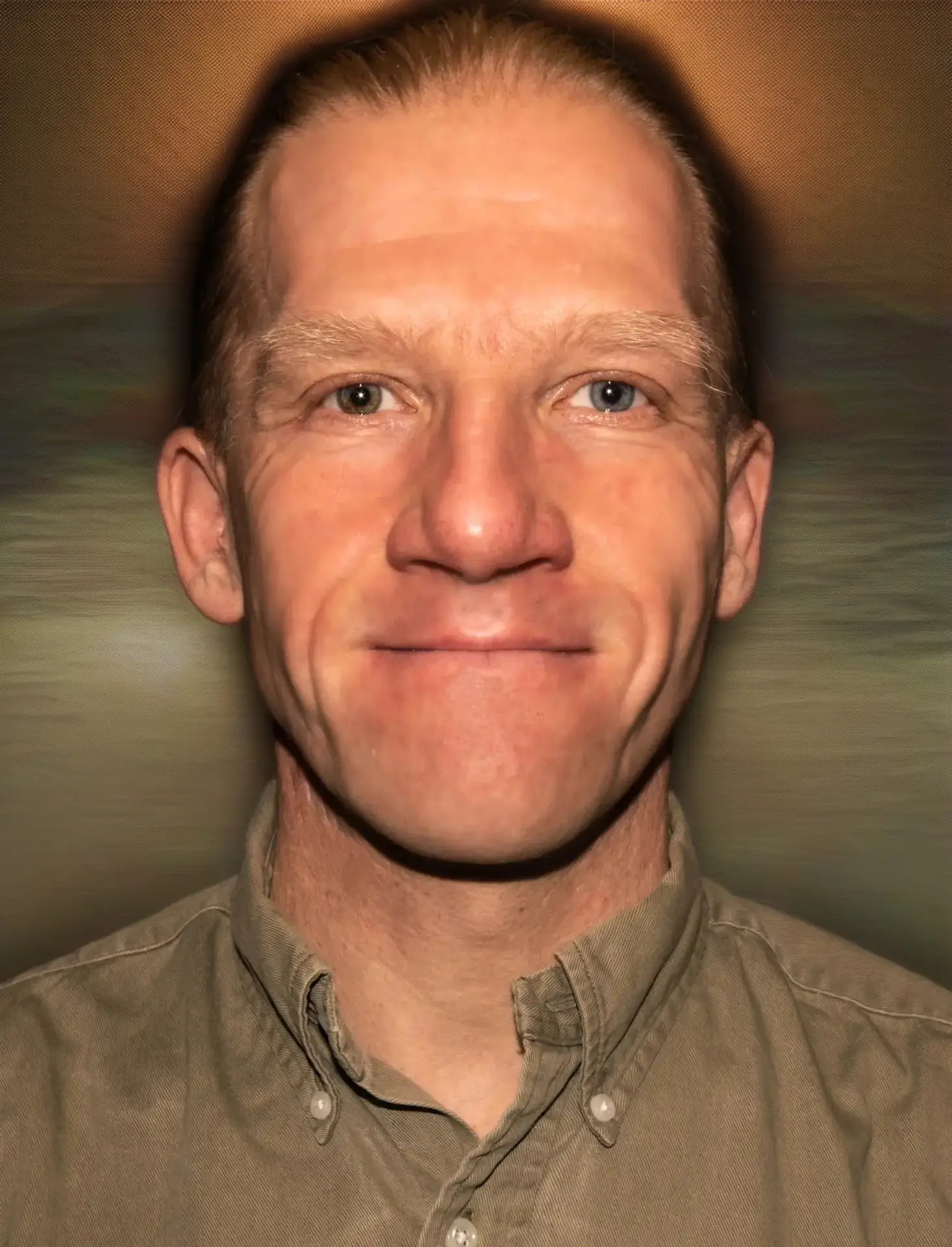 Portrait de Olivier Choumovsky, un homme caucasien aux cheveux courts blond et au visage souriant, portant une chemise kaki, sur fond noir. Intuici, Médecine Traditionnelle Chinoise, Genève.